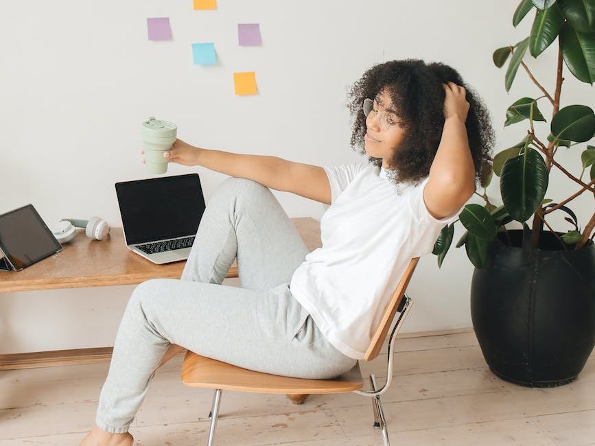 a woman sitting on a chair and holding a tumbler